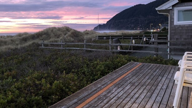 Una terraza de madera con vista a la playa y una montaña.