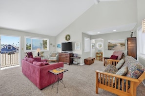 A spacious living room with a red sofa, a wooden bench, a television, and a fireplace.