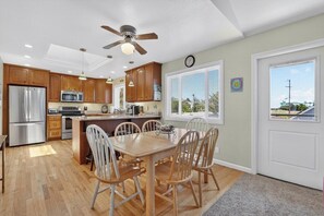 A kitchen with wooden cabinets, stainless steel appliances, a dining table with chairs, and a ceiling fan.