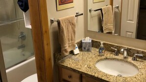 A bathroom with a granite countertop sink, wooden cabinets, a mirror, and a towel rack. - Newly Remodeled 2Bd, 2Ba/ Steps From The Super B-lift /ski rental/restaurant/bus (Frisco)
