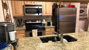 A kitchen with granite countertops, a stainless steel refrigerator, a microwave, an oven, and wooden cabinets. - Newly Remodeled 2Bd, 2Ba/ Steps From The Super B-lift /ski rental/restaurant/bus (Frisco)