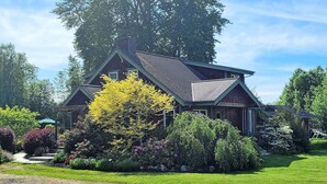 Ein zweigeschossiges Haus mit Satteldach, umgeben von einem gepflegten Garten mit verschiedenen Sträuchern und blühenden Pflanzen.