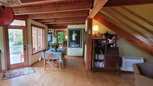Eine gemütliche Küche mit Holzbalken, einem Essbereich mit Tisch und Stühlen sowie einem Bücherregal voller Bücher.