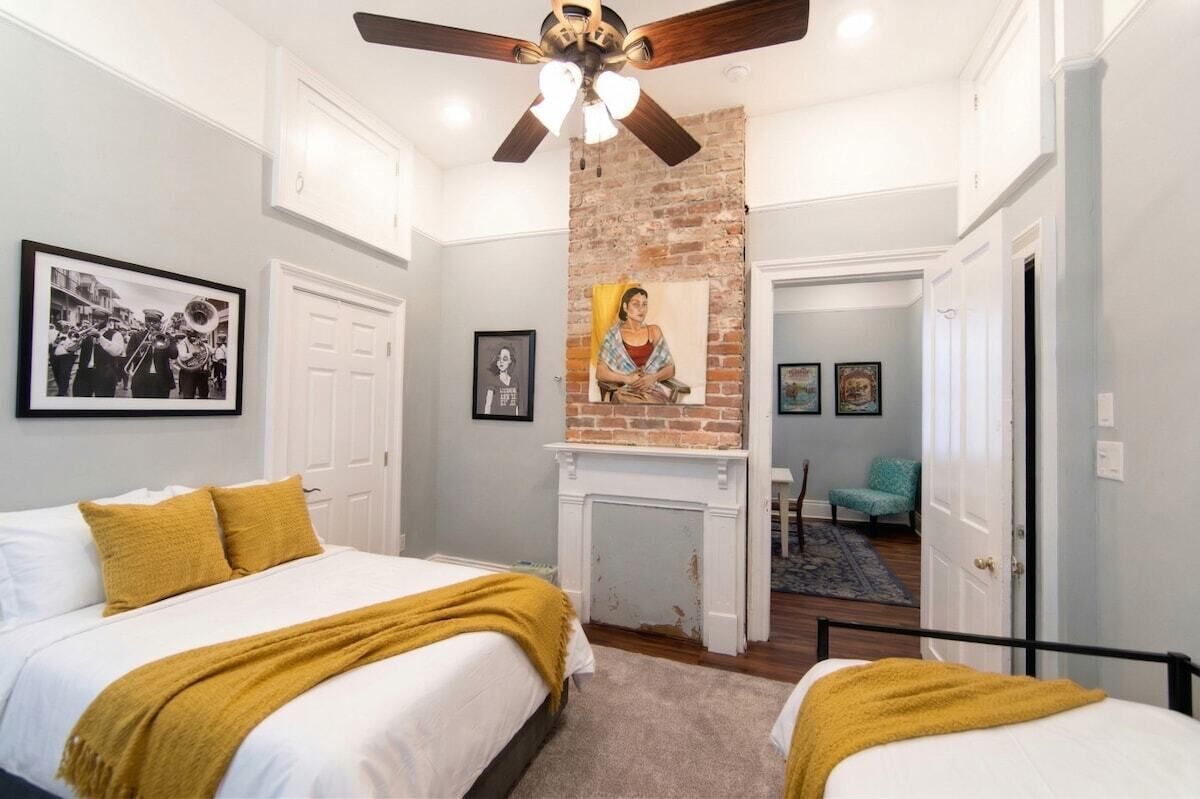 A bedroom with two beds, a fireplace, and a ceiling fan.