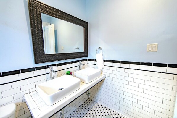 A bathroom with two sinks, a mirror, and a towel rack.