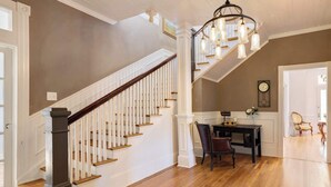 Una escalera con balaustres blancos y peldaños de madera que conduce a un comedor con una mesa y sillas.