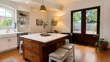 A kitchen with a central island, wooden cabinets, a sink, and a dining area with stools.