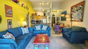 A living room with a blue sofa set, a wooden coffee table, and a kitchen in the background. - Spacious Condo w/ FREE WiFi, Parking, Heated Pool, Hot Tubs, Skier Shuttles (Avon)