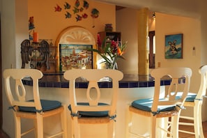 A dining area with white chairs and a blue-tiled bar counter.