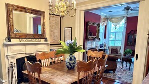 A dining room with a wooden table and chairs, a chandelier, and a fireplace.