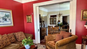 A living room with red walls, a brown sofa, a patterned armchair, and a floral rug.