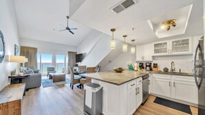 A modern kitchen with white cabinets, a central island, and pendant lighting. - Stunning Oceanfront on Crystal Beach with 2 King beds. Beach service included. (Destin)