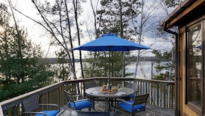 Una terrazza con tavolo e sedie, un barbecue e un bicchiere di birra.