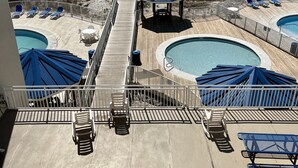 A pool area with multiple pools, lounge chairs, and umbrellas. - LOFT UNIT ON THE BEACH (Orange Beach)