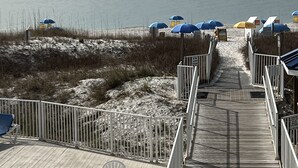 A wooden deck leading to beach umbrellas and a sandy beach area. - LOFT UNIT ON THE BEACH (Orange Beach)