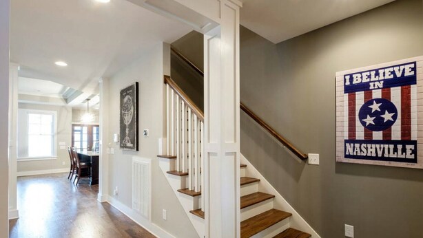 A staircase with wooden steps and white railings, leading to a room with a dining area and a wall with a 'I BELIEVE IN NASHVILLE' sign. - Walk to some of Nashville's best shopping ,dining and parks! Great for families (Nashville)