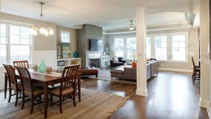 A spacious living room with a fireplace, a dining area with wooden chairs, and a kitchen area with a large window. - Walk to some of Nashville's best shopping ,dining and parks! Great for families (Nashville)