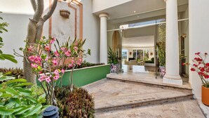 A hotel entrance with a marble staircase, columns, and potted plants.