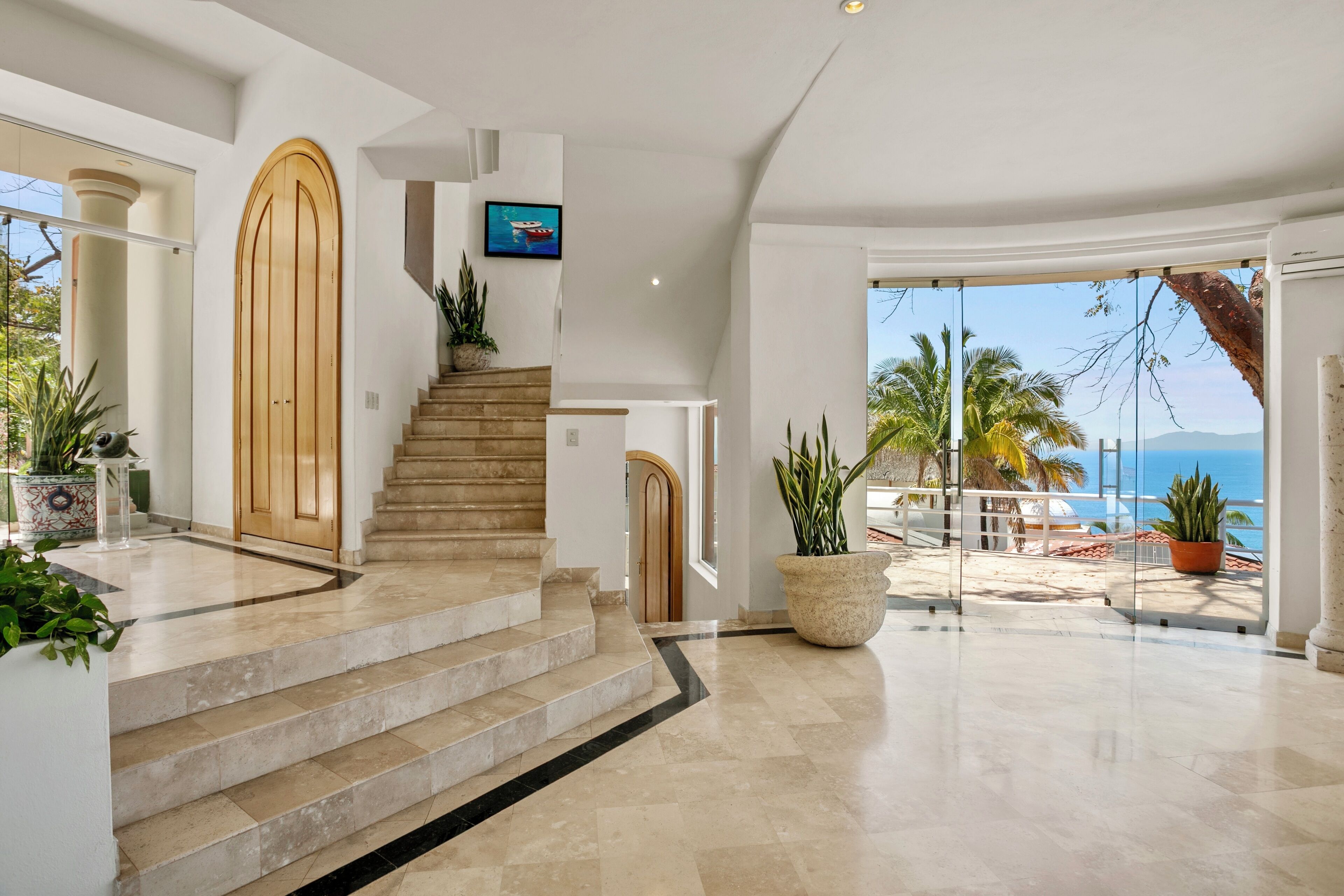Un intérieur moderne avec un escalier menant à un balcon d’où l’on a vue sur la mer.