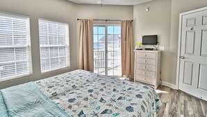 Ein Schlafzimmer mit einem Bett, einem Deckenventilator, einem Schminktisch und einem Fernseher.