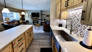 A compact kitchen with wooden cabinets, a central island, and a tiled backsplash.