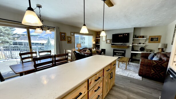 A modern kitchen with a large island, wooden cabinets, and pendant lighting.