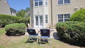 A two-story building with a beige exterior, large windows, and a small patio area with two lounge chairs. - Legends Golf Resort - 2 Bedroom on ground floor, Wi-Fi included (Myrtle Beach)