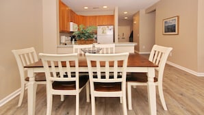 A dining area with a wooden table and four white chairs. - Legends Golf Resort - 2 Bedroom on ground floor, Wi-Fi included (Myrtle Beach)