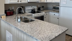 A kitchen with white cabinets, a granite countertop, a microwave, a stove, a toaster, and a refrigerator. - Legends Golf Resort - 2 Bedroom on ground floor, Wi-Fi included (Myrtle Beach)