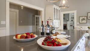 Una isla de cocina con cuencos de fruta, botellas de vino y vasos.