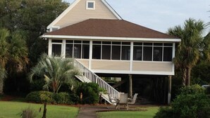 A two-story house with a covered porch, a staircase leading to the upper level, and a wooden deck.