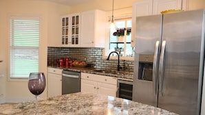 A kitchen with a granite countertop, stainless steel appliances, and white cabinetry.