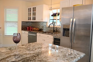 A kitchen with a granite countertop, stainless steel appliances, and white cabinetry. - One-of-a-Kind Luxury Lakefront Home; Waterfall Landscape; Exclusive Boat Rental (Lake Ozark)
