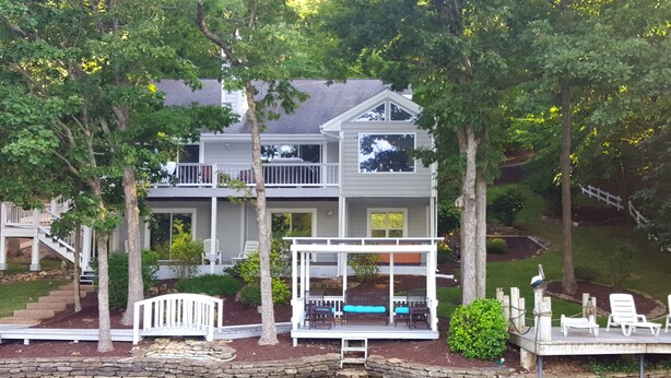 A two-story house with a dock and a covered seating area.