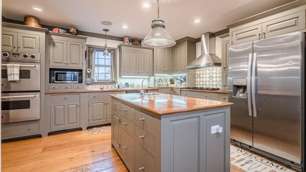 A modern kitchen with grey cabinets, stainless steel appliances, and a wooden island. - Special Rates-Enjoy Hot Springs in Our Colonial Williamsburg Reproduction Home (Hot Springs)