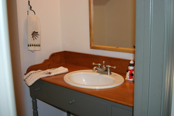 A bathroom with a wooden vanity, a white sink, and a mirror. - Special Rates-Enjoy Hot Springs in Our Colonial Williamsburg Reproduction Home (Hot Springs)