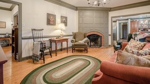 A living room with a fireplace, a sofa, a chair, and a table with a lamp. - Special Rates-Enjoy Hot Springs in Our Colonial Williamsburg Reproduction Home (Hot Springs)
