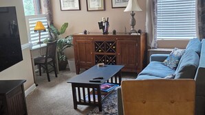 A living room with a sofa, a coffee table, a TV, a cabinet, and framed pictures on the wall. - Beautiful Condo - Water View Near City Dock  (Annapolis)
