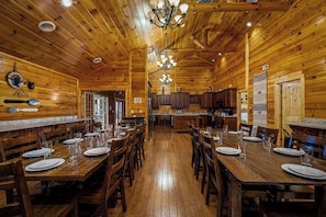 A wooden interior with a dining area, kitchen, and a chandelier.