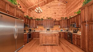A spacious kitchen with wooden cabinets, a stainless steel refrigerator, and a central island. - Swim Spa Pool - Hot Tub - Theater & Game Room - 5 mins to Pigeon Forge (Pigeon Forge)