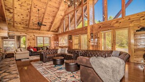 A spacious living room with a large sectional sofa, ottomans, and a patterned rug. - Swim Spa Pool - Hot Tub - Theater & Game Room - 5 mins to Pigeon Forge (Pigeon Forge)