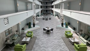 En rummelig atriumgård med et centralt siddeområde, flere balkoner og moderne møbler.