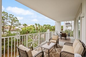 Relax on the balcony with a view of the beautifully landscaped garden, featuring wicker furniture and a charming garden setting.