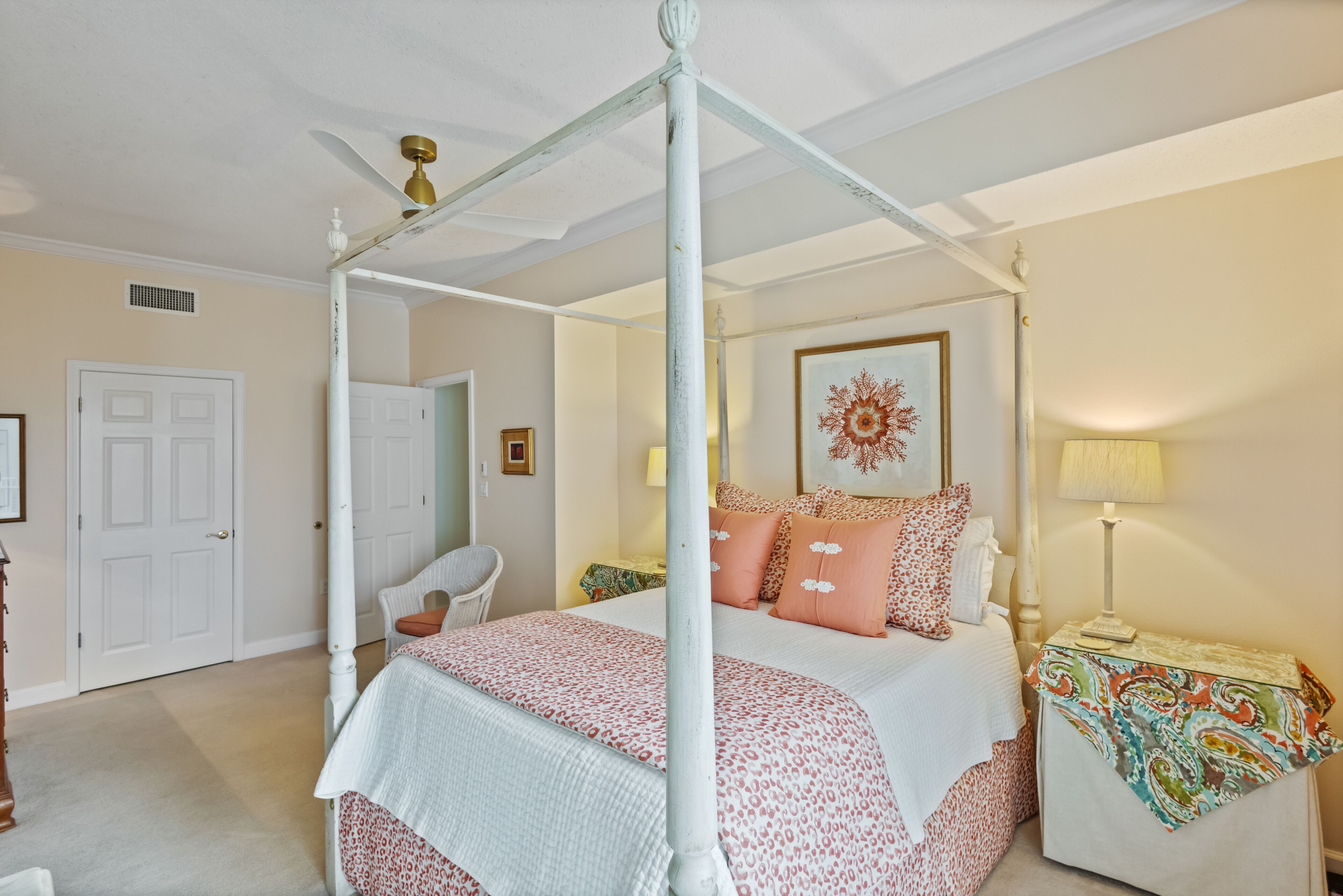 Quarto com uma cama de dossel, uma cadeira, uma mesinha de cabeceira e um abajur.