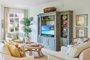 Relax in the living room with a sofa, armchairs, and a mounted TV.