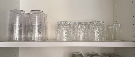 Un espace de rangement équipé d’étagères où sont disposés divers récipients transparents en verre.