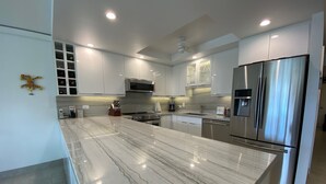 Una cocina moderna con encimera de mármol, electrodomésticos de acero inoxidable y armarios blancos.