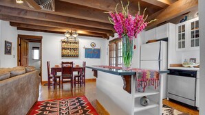 A modern kitchen with white cabinets, a built-in dishwasher, and a wooden ceiling.