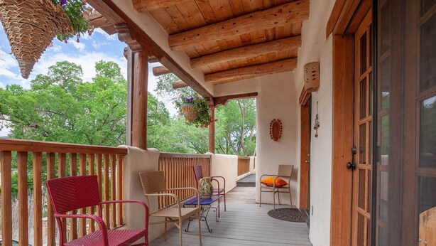 A wooden deck with wicker chairs and a table, overlooking a lush green landscape.