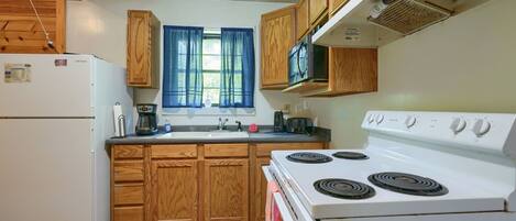 Una cocina con armarios de madera, una estufa blanca y un refrigerador.